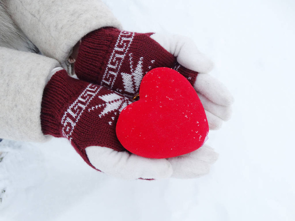 жіночі руки в рукавичках з червоним серцем на снігу
 - Фото, зображення