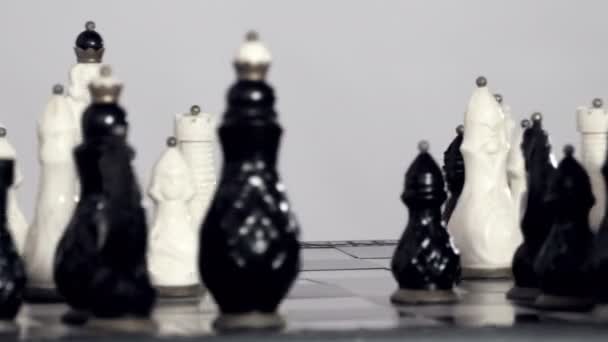 Шахматные фигуры белого и черного цвета разбросаны по доске
 - Кадры, видео