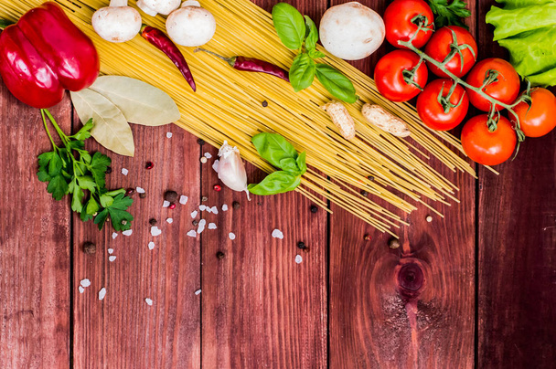 Droge pasta met tomaten, kruiden en specerijen voor tomatensaus, op houten achtergrond, bovenaanzicht - Foto, afbeelding