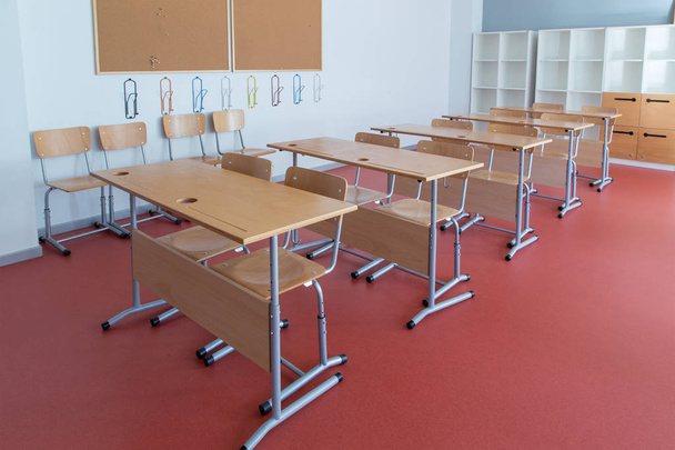 Sala de aula vazia com mesas e cadeiras de madeira
 - Foto, Imagem