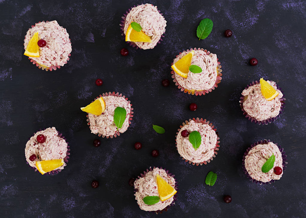 Zitronen-Cupcakes mit Kirschcreme. Preiselbeere, Minzblätter. Essen auf dunklem Hintergrund. Ansicht von oben - Foto, Bild