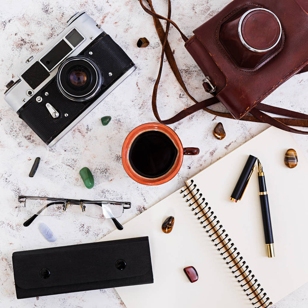 Flat lay, top view office table desk. Desk workspace with retro camera, diary, pen, glasses, case, cup of coffee on white background. - Fotoğraf, Görsel