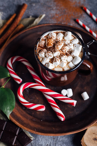 Vintage mug of hot chocolate with cinnamon sticks over dark background - Foto, Imagem