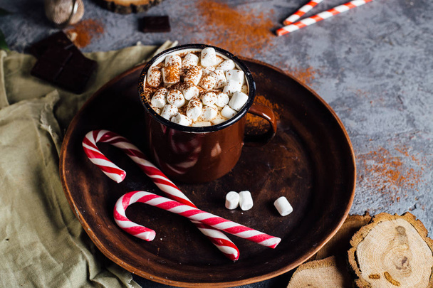 Vintage mug of hot chocolate with cinnamon sticks over dark background - Zdjęcie, obraz