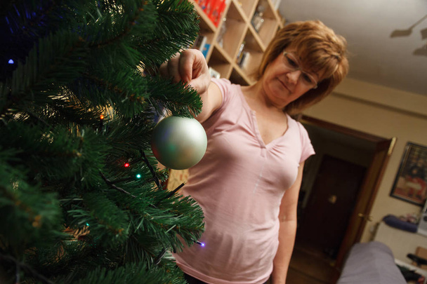 大人の女性、母、カラフルなボールでクリスマス ツリーを飾る. - 写真・画像