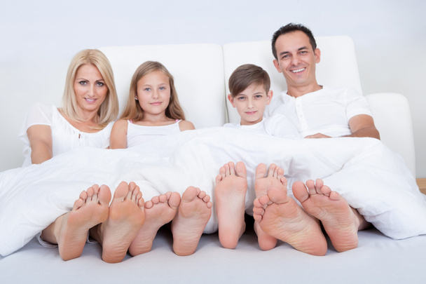 Happy Family In Bed Under Cover Showing Feet - Фото, изображение