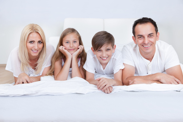 Happy Family With Two Children Lying On Bed - Φωτογραφία, εικόνα