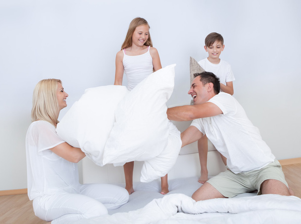 Family Having A Pillow Fight Together On Bed - Foto, afbeelding