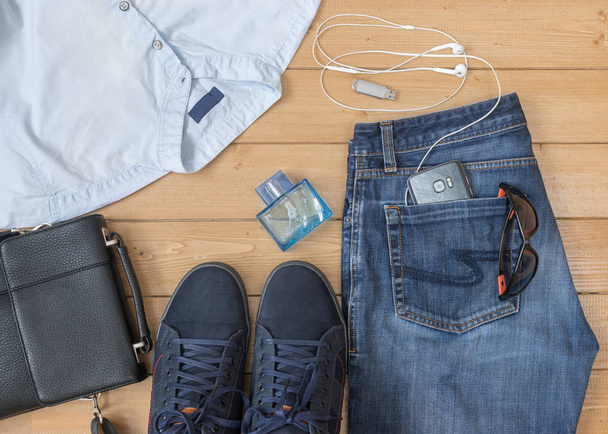 Men's jeans and accessories on the wooden floor. - Photo, Image