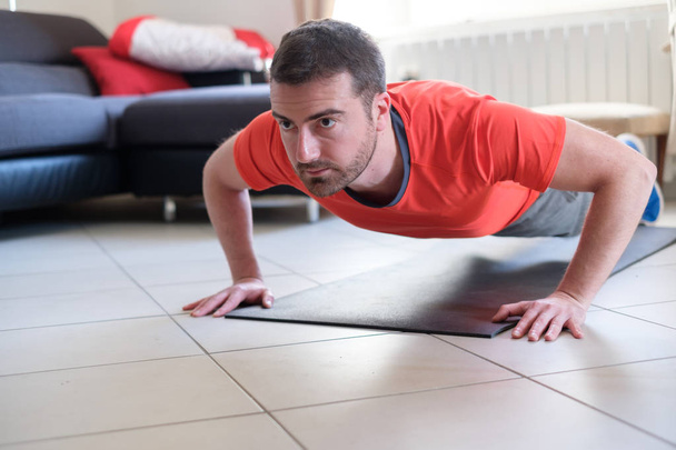 Mann macht Körperübungen und trainiert zu Hause - Foto, Bild