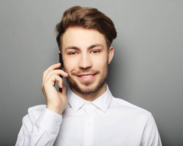 happy business man calling with his smartphone against grey  bac - Zdjęcie, obraz