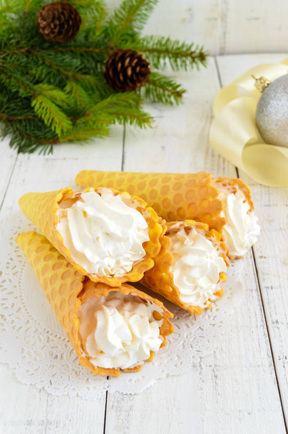 knusprige Honigwaffeln in Form von Zapfen, gefüllt mit Luft-Vanillecreme (Eis) auf weißem Hintergrund. Nahaufnahme. Leckereien für die Party. - Foto, Bild