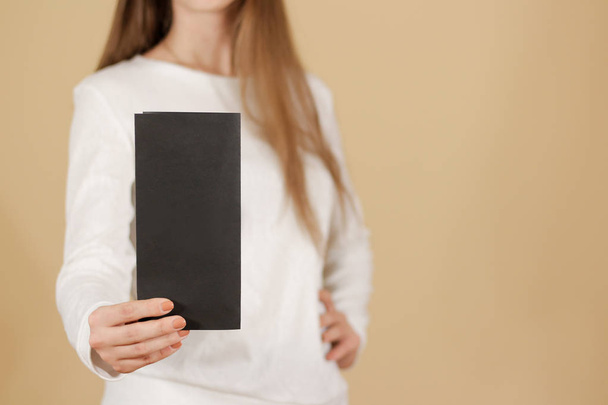 Girl showing blank black flyer brochure booklet. Leaflet present - 写真・画像