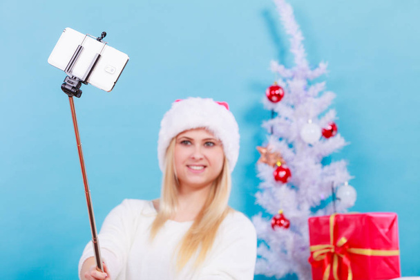 Woman in Santa hat taking Christmas selfie - Foto, Imagen