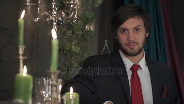 Portrait of brutal bearded man in a suit with a red tie in a romantic atmosphere by candlelight. - Filmmaterial, Video