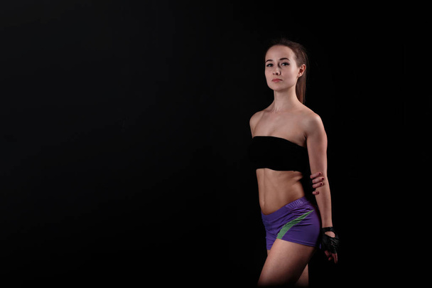 Sport girl stands and stares at camera against black background. - Photo, image