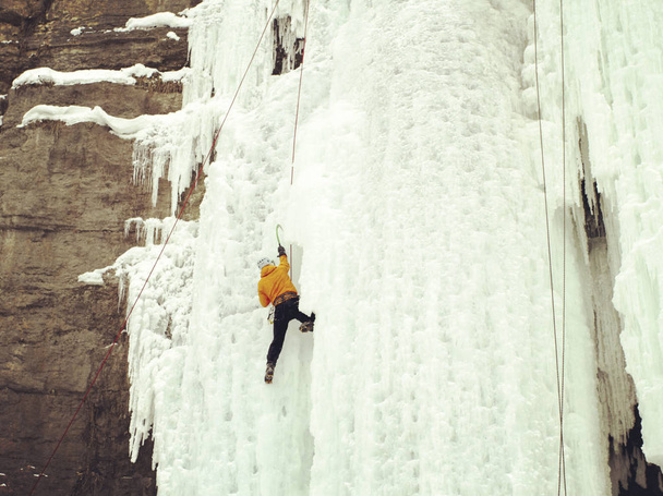 Ice climbing.Man climbing frozen waterfall. - Photo, Image
