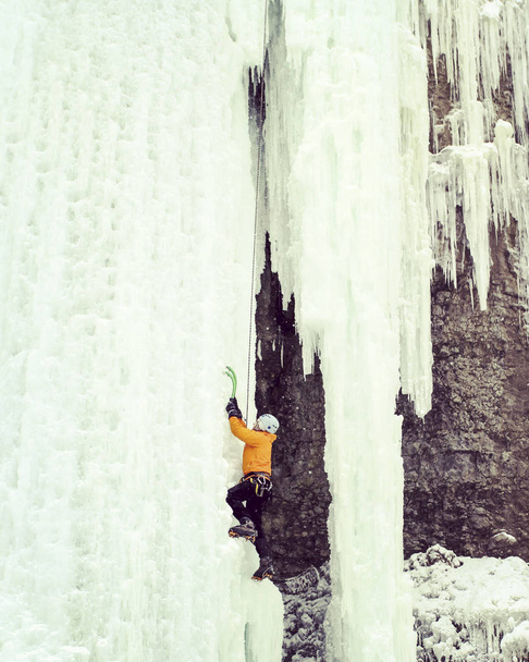 Ice climbing.Man climbing frozen waterfall. - Zdjęcie, obraz