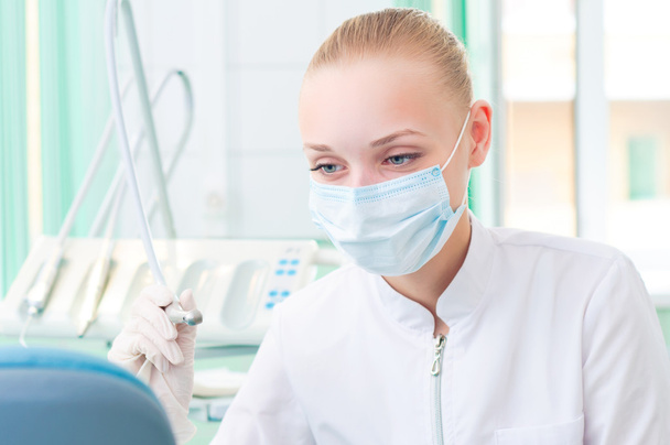 Female dentists in protective mask holds a dental drill - Photo, image