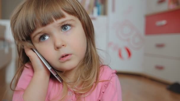 Kis baba gyerek, mint egy felnőtt, beszél egy okostelefon a szobájában a szőnyegen ülve - Felvétel, videó