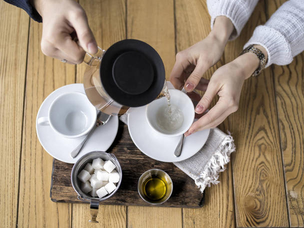 Tazze di tè versate a mano, bollitore con tè, zucchero, miele su sfondo di legno. Vista dall'alto
. - Foto, immagini