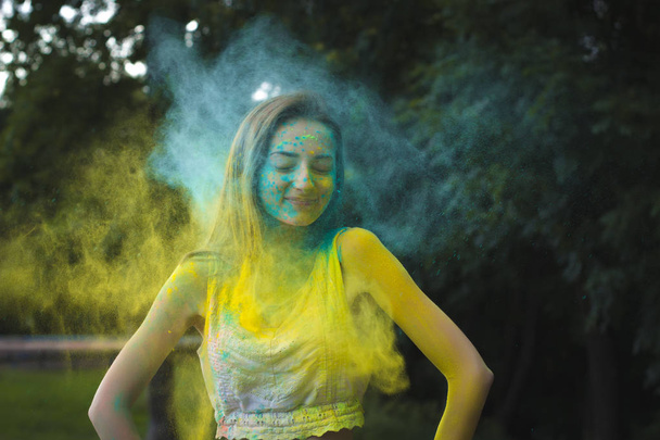 Mujer sonriente con polvo Holi explotando a su alrededor
 - Foto, Imagen