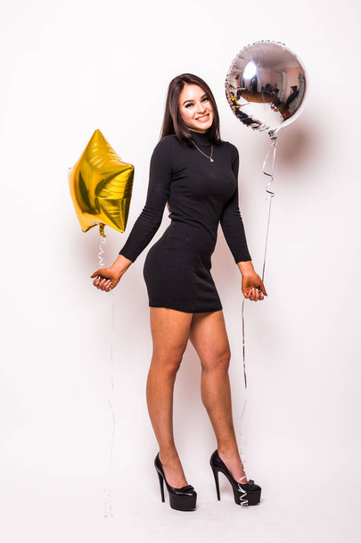 Pretty young woman in black dress with gold star shaped balloon smiling and drinking champagne - Фото, изображение
