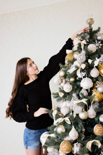 Beautiful girl decorates the Christmas tree - Fotoğraf, Görsel