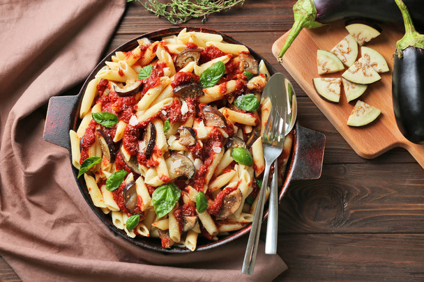 Pan with tasty macaroni, napkin, kitchen board and products - Photo, image