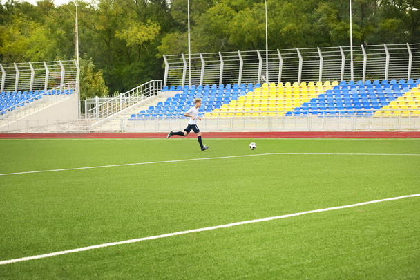 Boy playing football at stadium - Foto, Imagen