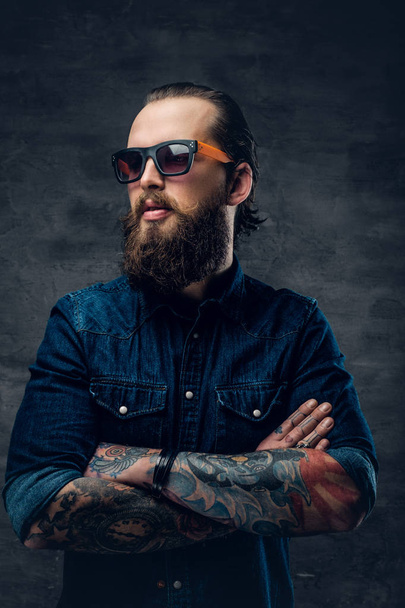 Hombre en gafas de sol con brazos cruzados tatuados
 - Foto, Imagen