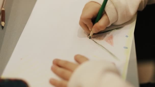 Closeup of little girl drawing with pencils on a paper - Materiał filmowy, wideo