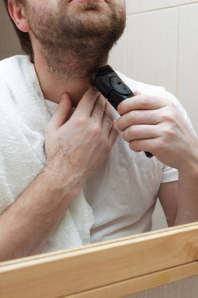 Junger Mann mit Bart rasiert Stoppeln mit Rasiermesser. - Foto, Bild