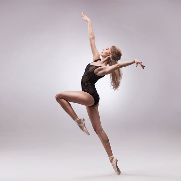 Ballerina in black outfit posing on toes - Foto, Imagen