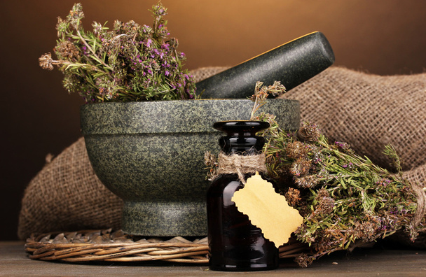 Thyme herb and mortar on wooden table on brown background - Фото, зображення
