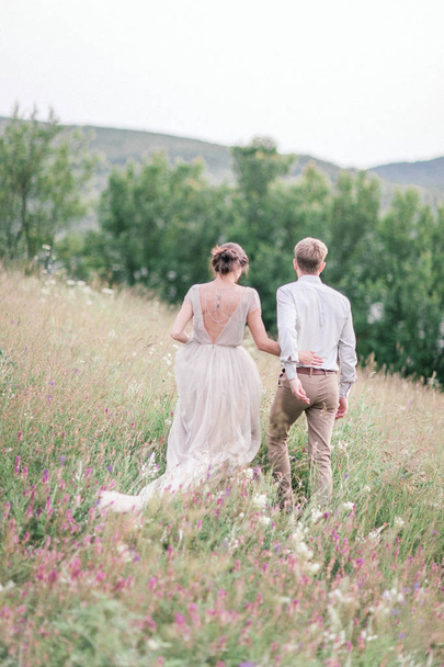 Couple in wedding attire with a bouquet of flowers and greenery  - Fotoğraf, Görsel