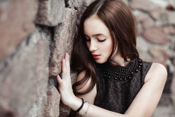 krásná smutná mladá žena na pozadí kamenné zdi - Fotografie, Obrázek