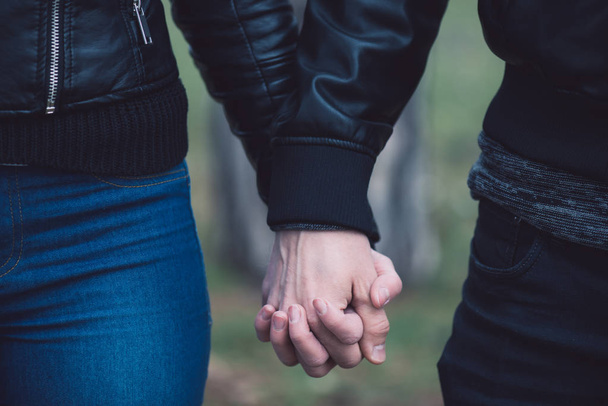 Conceptual image of female and male hands together. Young couple in love walking in the park holding hands. - Foto, Imagen