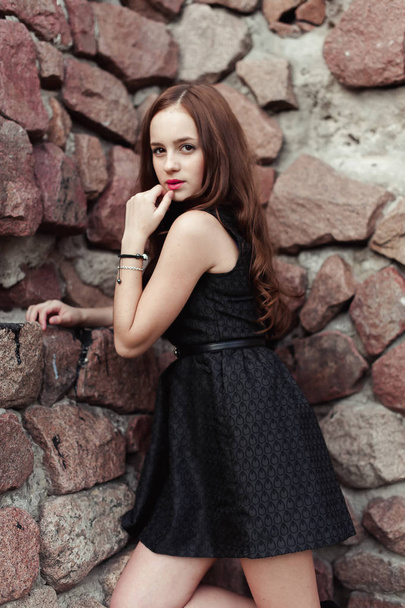 beautiful sad young woman on a stone wall background - 写真・画像