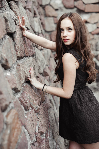 石の壁の背景に美しい悲しい若い女性 - 写真・画像