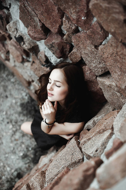 beautiful sad young woman on a stone wall background - Photo, Image