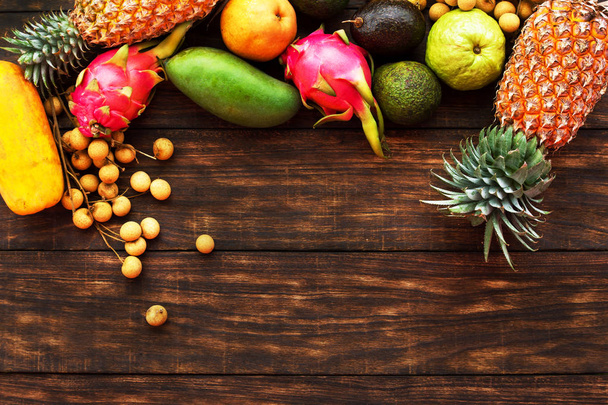 Tropical fruit on dark wooden background, top view - Foto, imagen