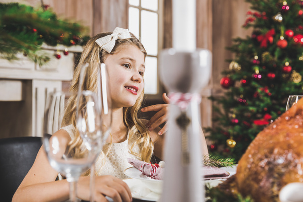 Cute girl at holiday table    - Foto, afbeelding