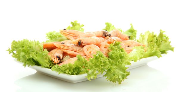 Boiled shrimps with lettuce leaves on plate, isolated on white - Foto, afbeelding