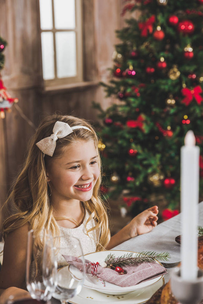 Cute girl at holiday table     - Foto, afbeelding
