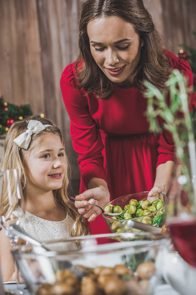 Woman putting brussel sprouts on plate - 写真・画像