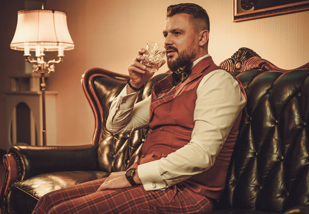 ウイスキーのグラスを持つ贅沢なスタイリッシュな男  - 写真・画像
