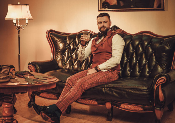 Экстравагантный стильный мужчина со стаканом виски
  - Фото, изображение