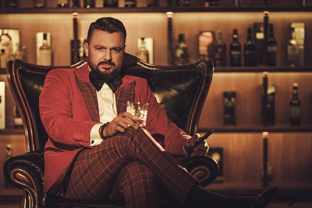 Extravagante stijlvolle man met glas whisky  - Foto, afbeelding