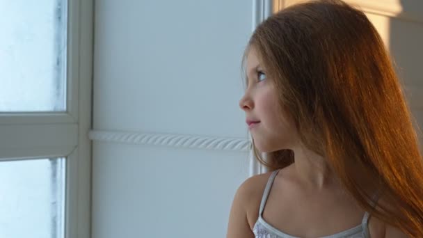 Winter Day. Girl looking out the window at the falling snow - Filmagem, Vídeo